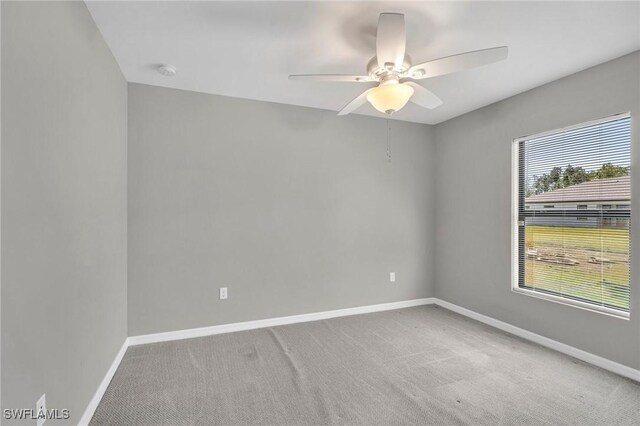 empty room featuring baseboards, a ceiling fan, and light carpet