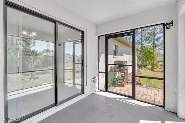doorway to outside featuring finished concrete floors and a notable chandelier