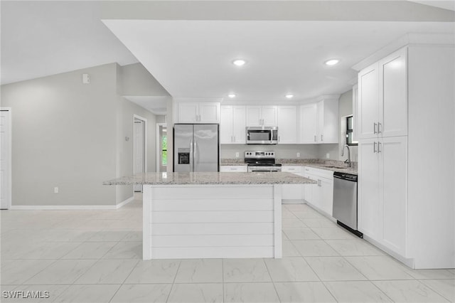 5303 4th St W, Lehigh Acres, FL 33971 - kitchen with stainless steel appliances, a center island, light marble finish flooring, white cabinetry, and light stone countertops