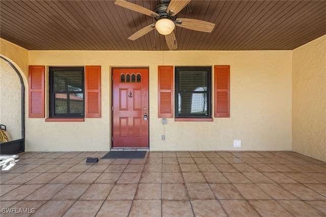 entrance to property featuring stucco siding, a patio, and a ceiling fan