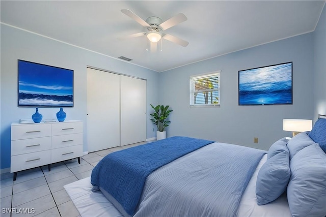 bedroom with light tile patterned floors, visible vents, a closet, and a ceiling fan