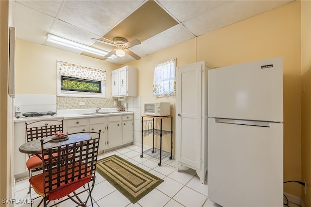 kitchen with ceiling fan, light countertops, light tile patterned flooring, white appliances, and a sink