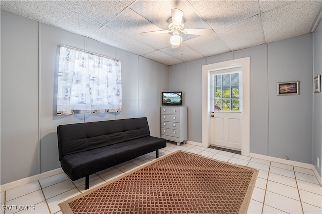 living area with a decorative wall, light tile patterned flooring, and a paneled ceiling