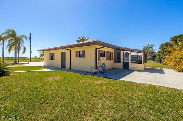 view of front of property featuring stucco siding, a front lawn, and a sunroom