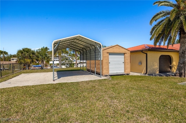 view of outdoor structure featuring a detached carport, driveway, and fence