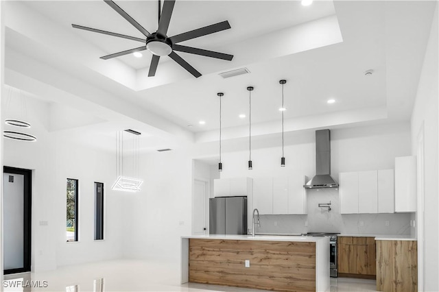 kitchen with visible vents, appliances with stainless steel finishes, a raised ceiling, wall chimney exhaust hood, and modern cabinets