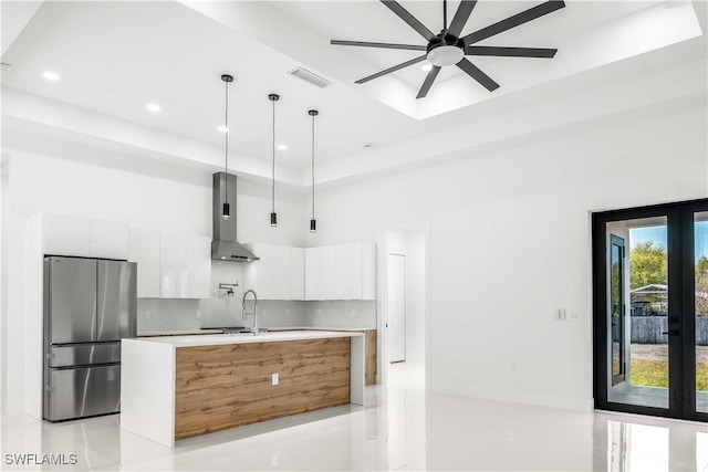 kitchen featuring visible vents, modern cabinets, freestanding refrigerator, french doors, and wall chimney range hood