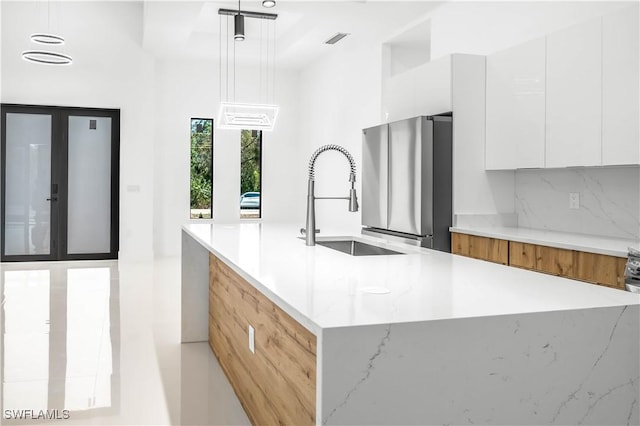 kitchen featuring backsplash, freestanding refrigerator, white cabinets, modern cabinets, and a sink