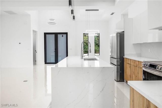 kitchen with pendant lighting, an island with sink, appliances with stainless steel finishes, modern cabinets, and a sink