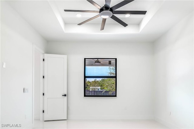 empty room featuring a raised ceiling and a ceiling fan