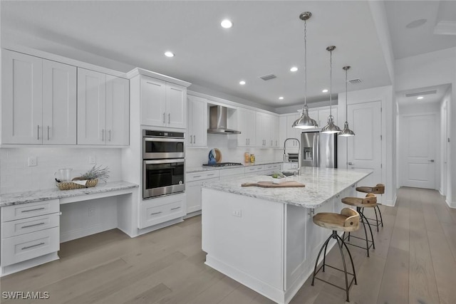 10111 Palazzo Dr, Naples, FL 34119 - kitchen with wall chimney range hood, stainless steel appliances, white cabinets, recessed lighting, and light wood-type flooring