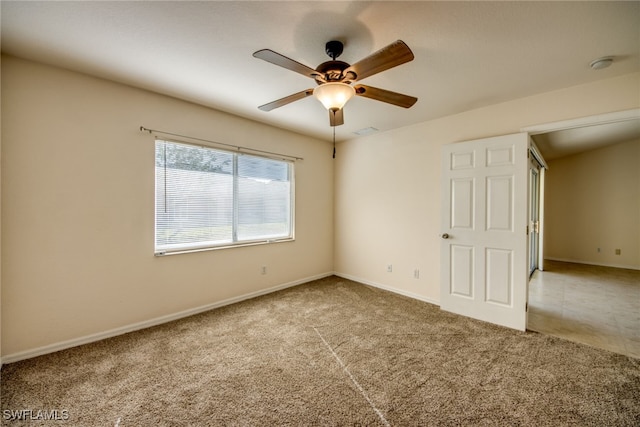 empty room with visible vents, carpet floors, baseboards, and ceiling fan