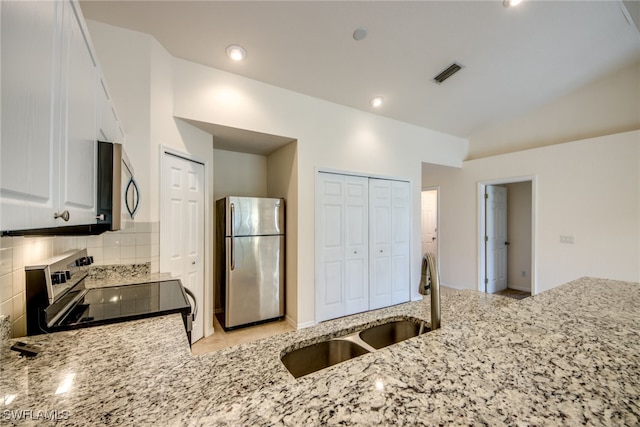 kitchen with light stone countertops, visible vents, a sink, decorative backsplash, and stainless steel appliances