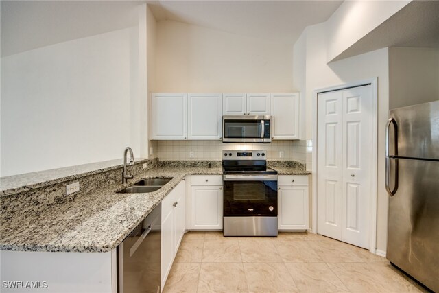 kitchen with light stone counters, a sink, decorative backsplash, stainless steel appliances, and white cabinets