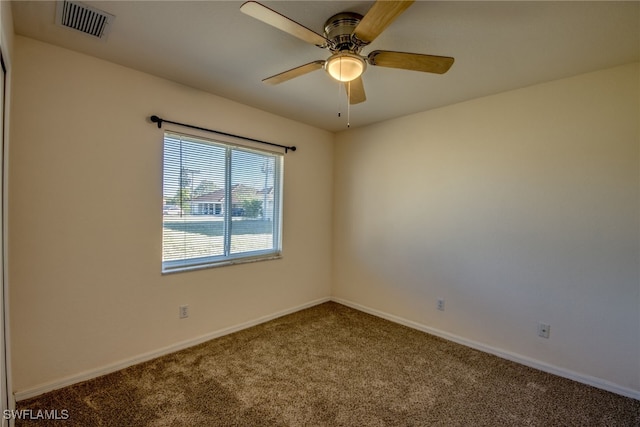 carpeted spare room featuring visible vents, baseboards, and ceiling fan