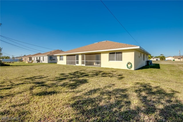 back of house featuring a yard, a sunroom, and stucco siding