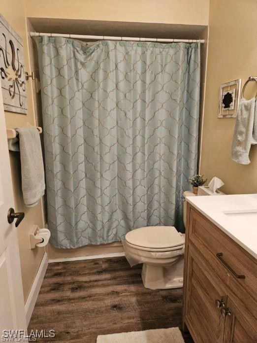 full bath with toilet, vanity, and wood finished floors