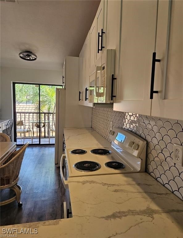 kitchen with tasteful backsplash, light stone countertops, white cabinets, white appliances, and dark wood-style flooring