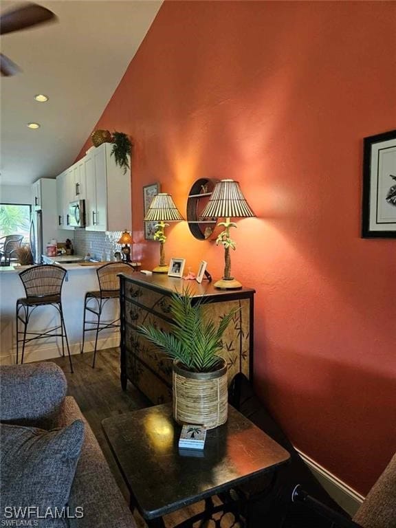 interior space featuring baseboards, decorative backsplash, wood finished floors, stainless steel appliances, and a ceiling fan