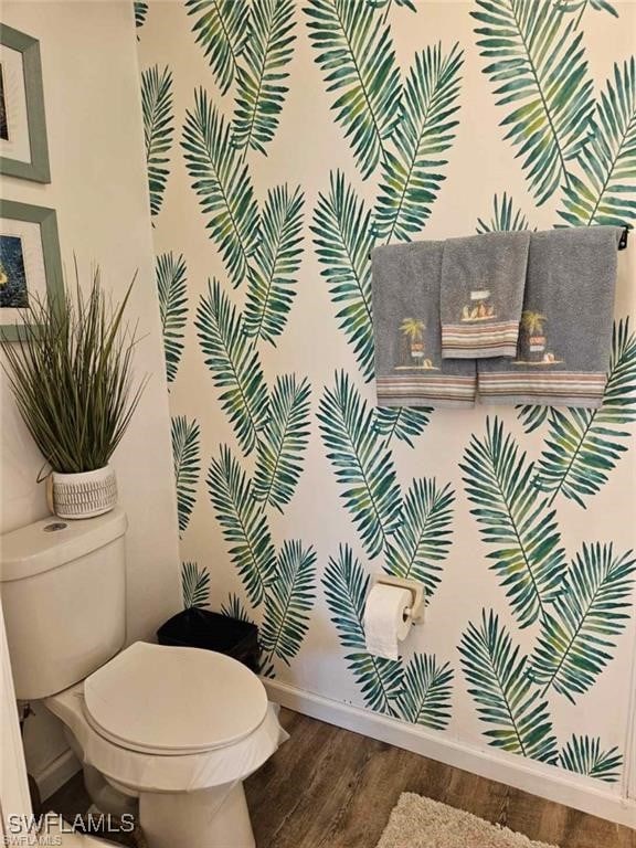 bathroom with toilet, baseboards, and wood finished floors