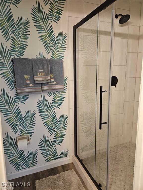 full bathroom with wood finished floors, a stall shower, and baseboards