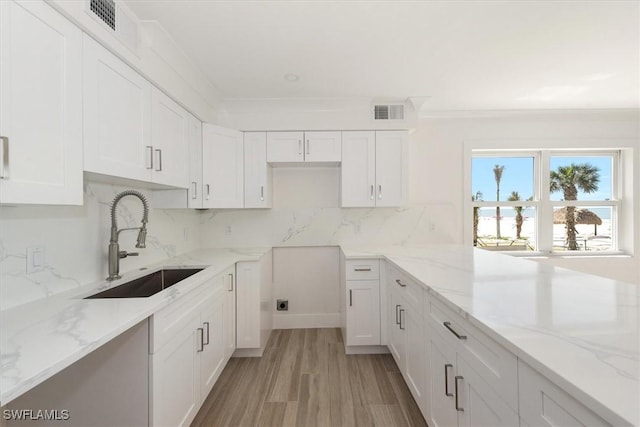 kitchen with white cabinets, visible vents, tasteful backsplash, and a sink