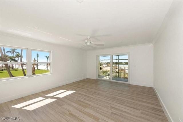 empty room featuring crown molding, a ceiling fan, baseboards, and light wood finished floors