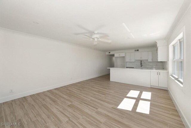 kitchen featuring light wood-style flooring, backsplash, white cabinets, light countertops, and baseboards