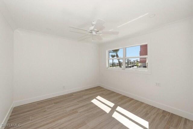 empty room featuring baseboards, light wood-style flooring, a ceiling fan, and crown molding