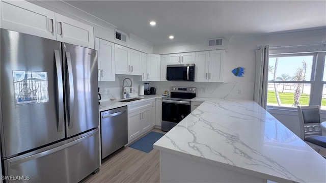 100 Estero Blvd Unit 131, Fort Myers Beach, FL 33931 - kitchen featuring appliances with stainless steel finishes, a sink, white cabinetry, light stone counters, and recessed lighting