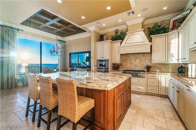 kitchen with custom exhaust hood, visible vents, coffered ceiling, and stone tile flooring