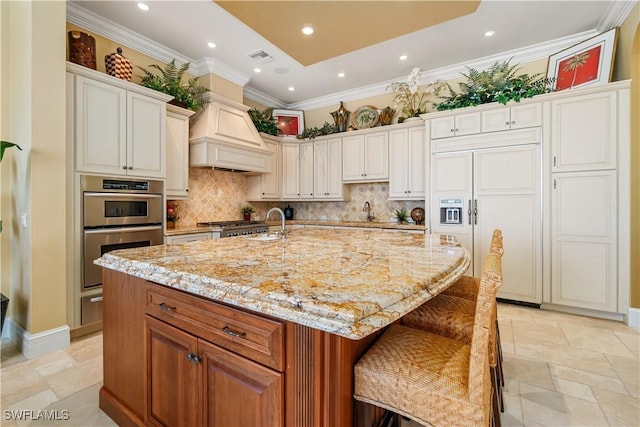 kitchen featuring tasteful backsplash, light stone countertops, custom range hood, paneled built in fridge, and stainless steel double oven