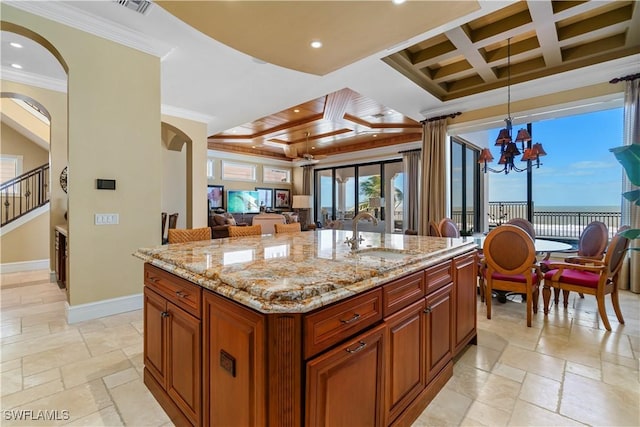 kitchen with stone tile floors, coffered ceiling, baseboards, and a sink