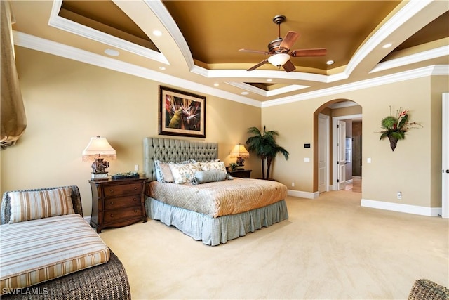 carpeted bedroom featuring arched walkways, baseboards, a tray ceiling, and ornamental molding