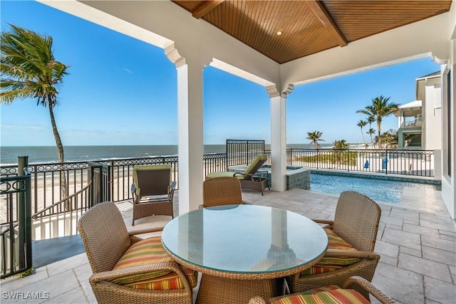 view of patio / terrace featuring outdoor dining space, a pool with connected hot tub, and a water view