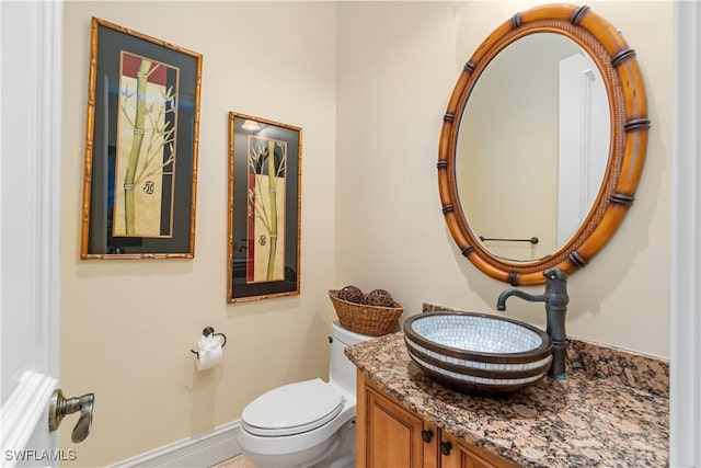 bathroom with toilet, vanity, and baseboards