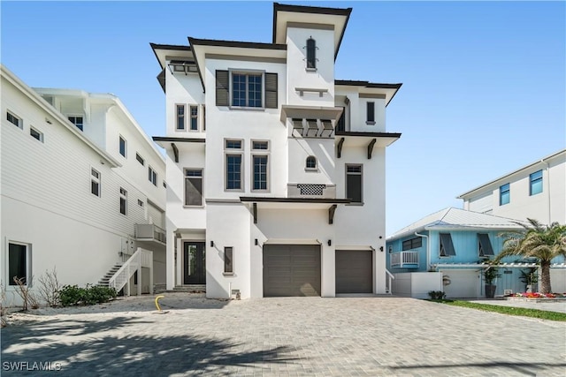 view of front facade featuring stairway, stucco siding, an attached garage, and decorative driveway