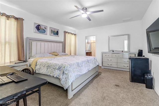 bedroom featuring light carpet, ensuite bathroom, and ceiling fan