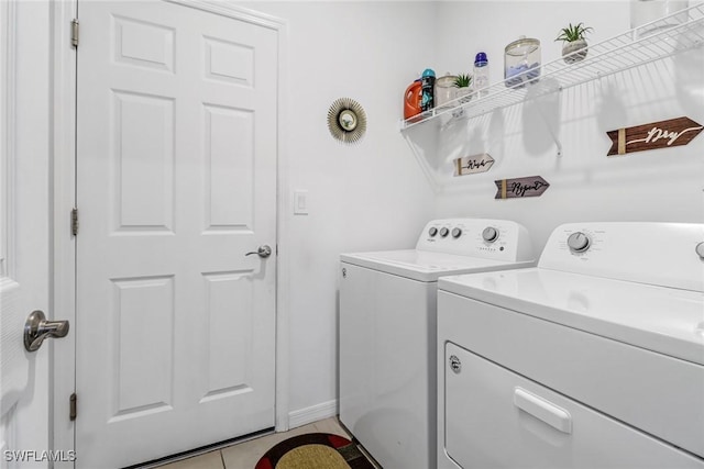 clothes washing area with laundry area, light tile patterned flooring, washing machine and dryer, and baseboards