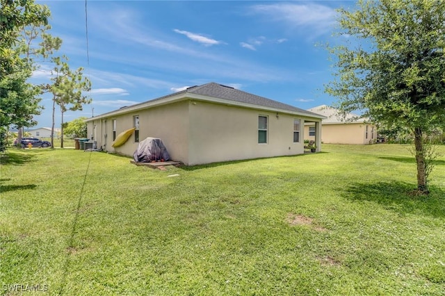 back of property featuring a lawn and stucco siding