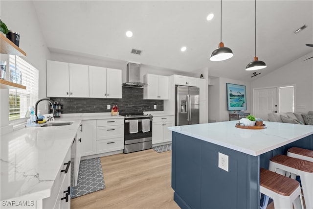 kitchen with a sink, wall chimney range hood, visible vents, and stainless steel appliances