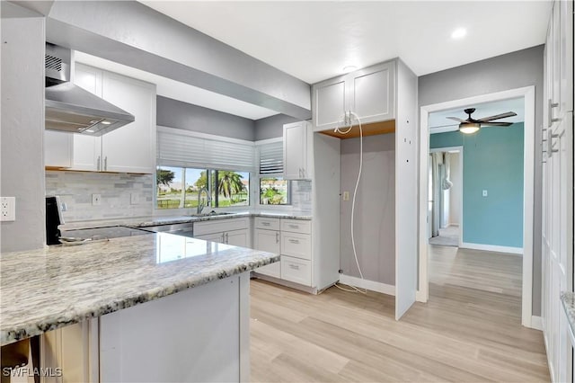 kitchen with electric range, light stone counters, exhaust hood, and backsplash