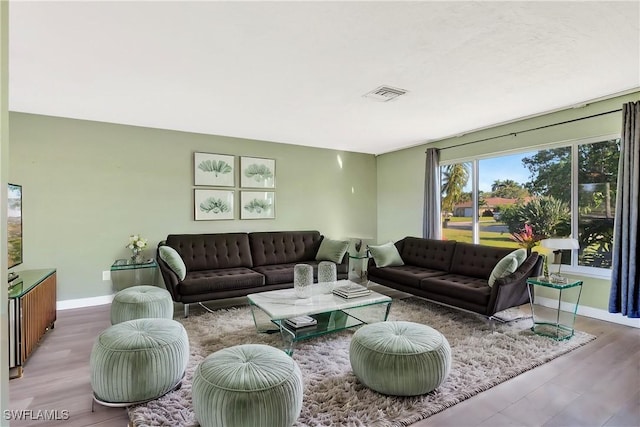 living room with wood finished floors, visible vents, and baseboards