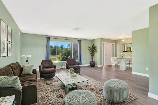 living area with wood finished floors, visible vents, and baseboards