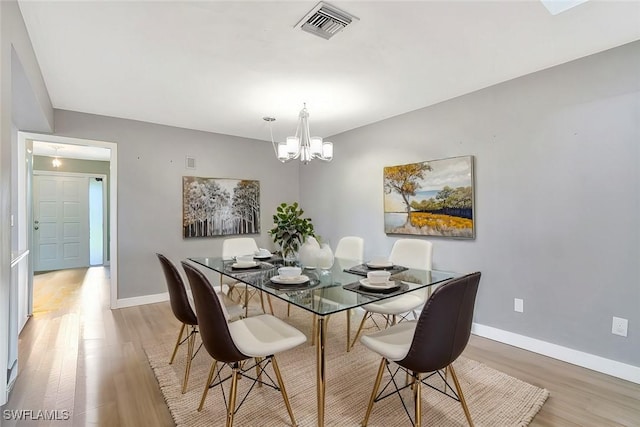 dining room with light wood-style floors, visible vents, a chandelier, and baseboards