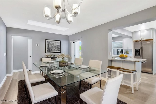 dining room with baseboards, a notable chandelier, and light wood-style flooring