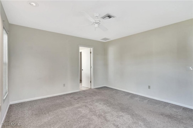 spare room with light carpet, visible vents, baseboards, and a ceiling fan