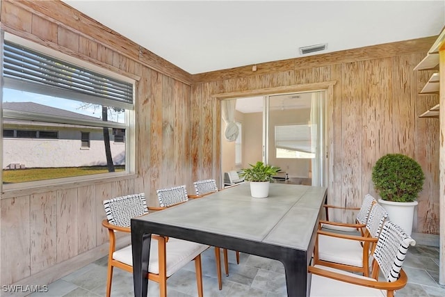 dining room with visible vents and wood walls