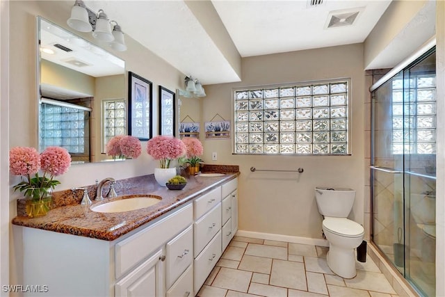 bathroom featuring visible vents, toilet, a sink, a shower stall, and double vanity