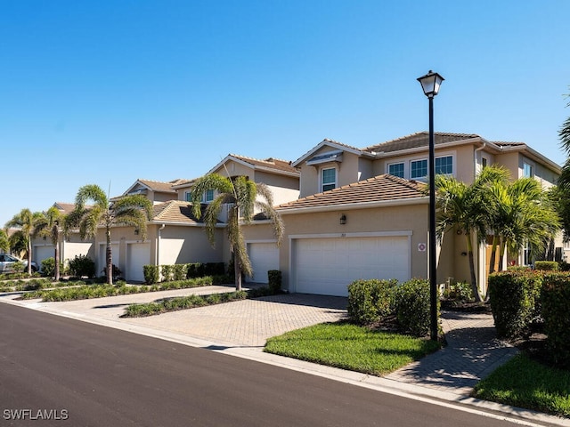 view of front of house with stucco siding, decorative driveway, a garage, and a tile roof